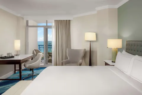 Palm Beach Club room king bed with balcony and ocean beyond at Hilton Aruba Caribbean Resort and Casino.