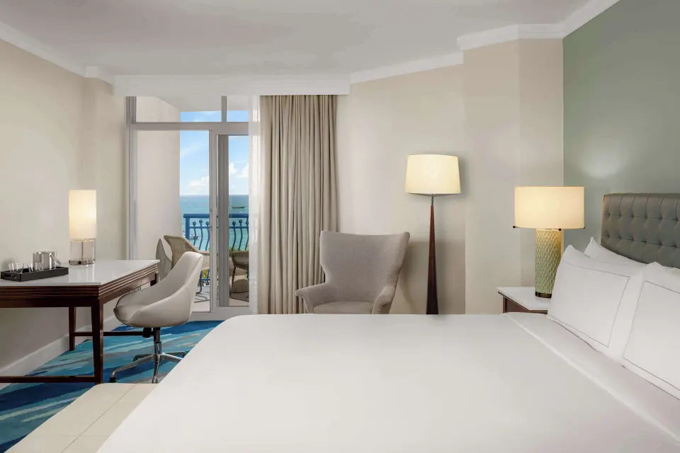 Palm Beach Club room king bed with balcony and ocean beyond at Hilton Aruba Caribbean Resort and Casino.