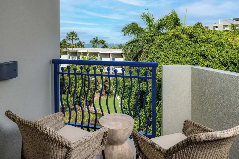 Partial ocean view balcony with wicker chairs and blue railing at Hilton Aruba Caribbean Resort and Casino.