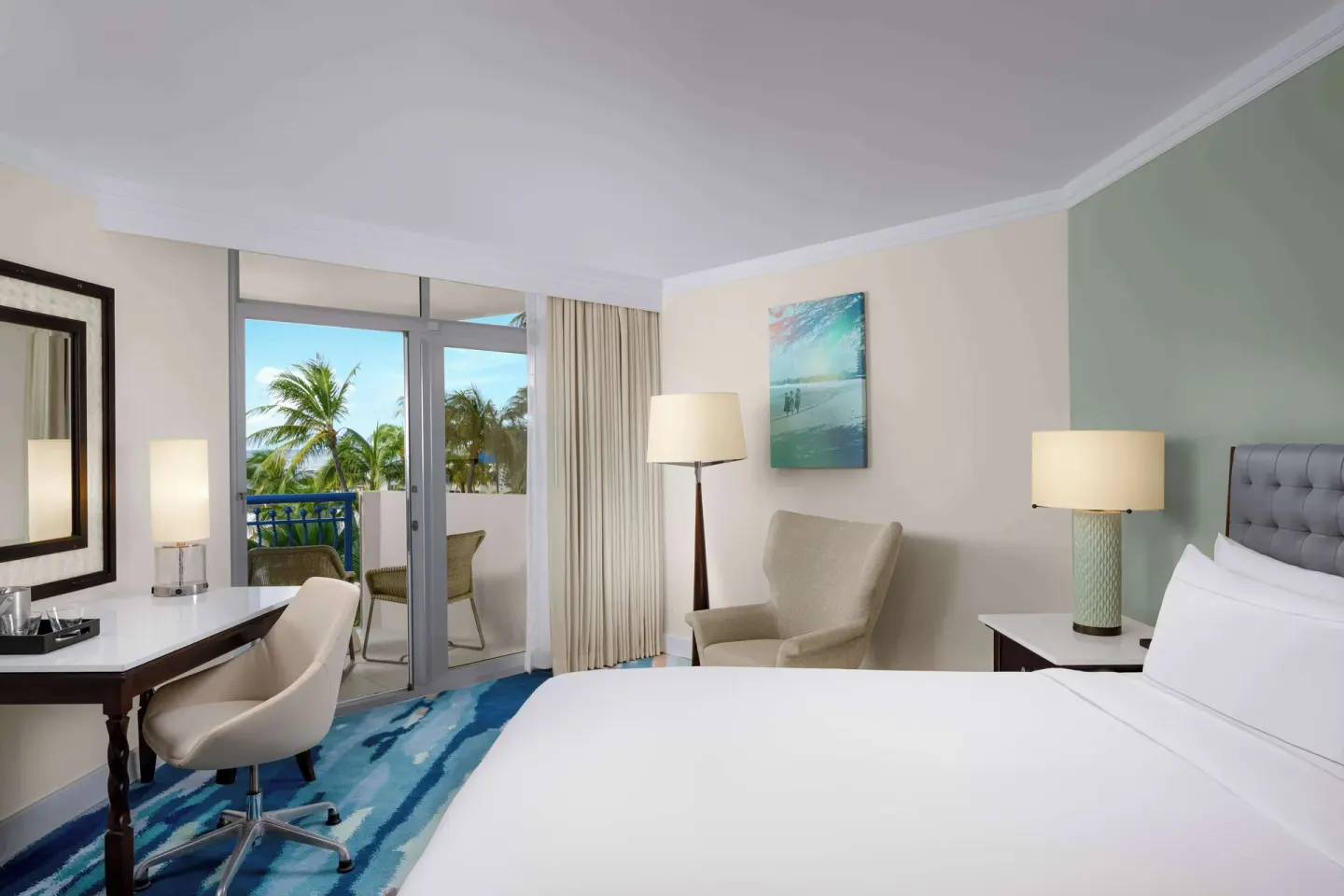 Partial ocean view guest room with king bed, desk, chair, and balcony at Hilton Aruba Caribbean Resort and Casino.