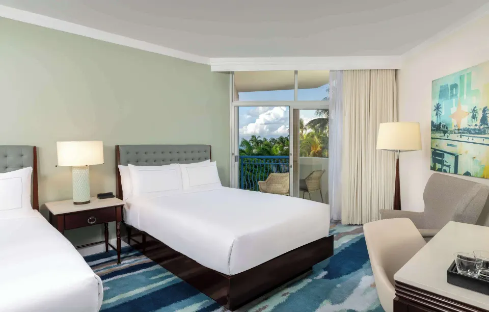 Partial ocean view guest room with two beds and balcony at Hilton Aruba Caribbean Resort and Casino.