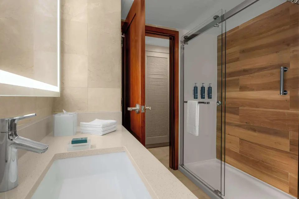 Guest room bathroom with sink and glass shower at Hilton Aruba Caribbean Resort and Casino.