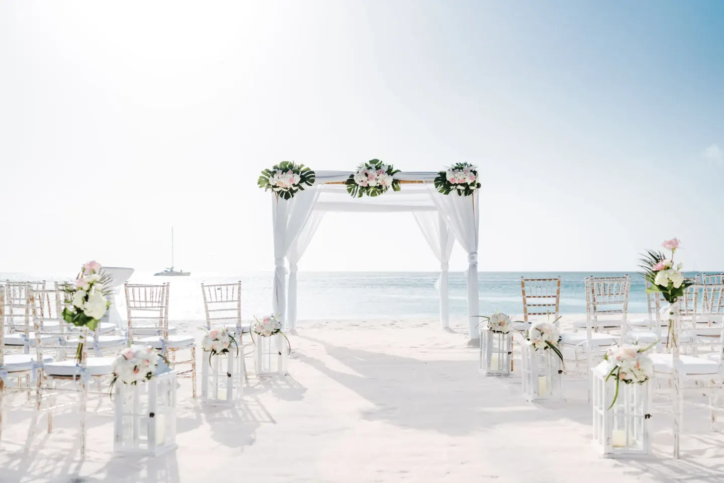 Beach wedding arch and white chairs at Hilton Aruba Caribbean Resort and Casino.