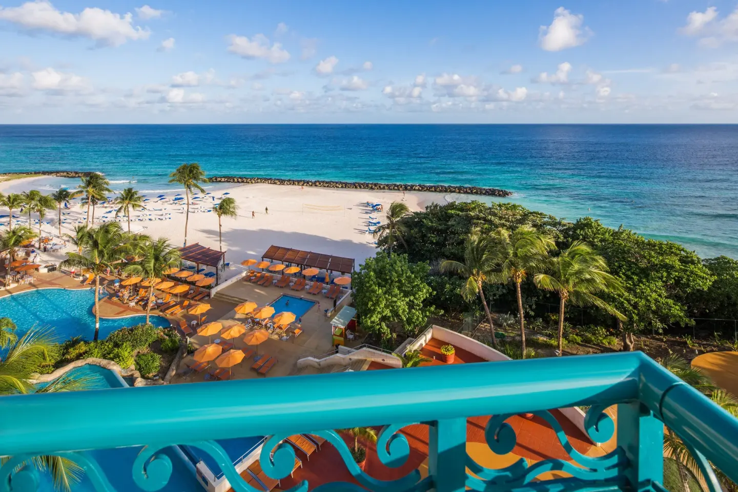 Balcony view of beach, pools, palms, and ocean at Hilton Barbados Resort.