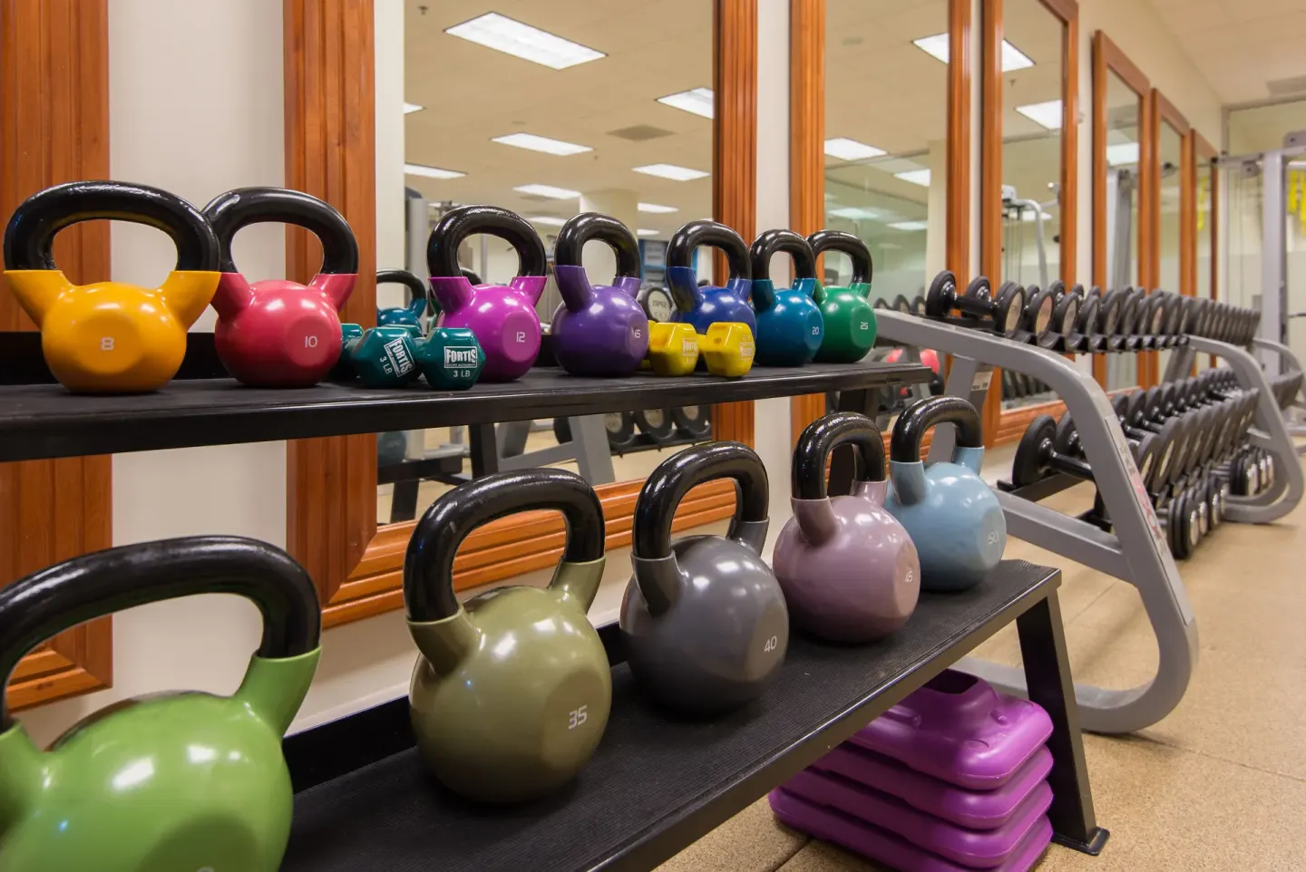 Colorful kettlebells and dumbbells on racks in the fitness center at Hilton Barbados Resort.