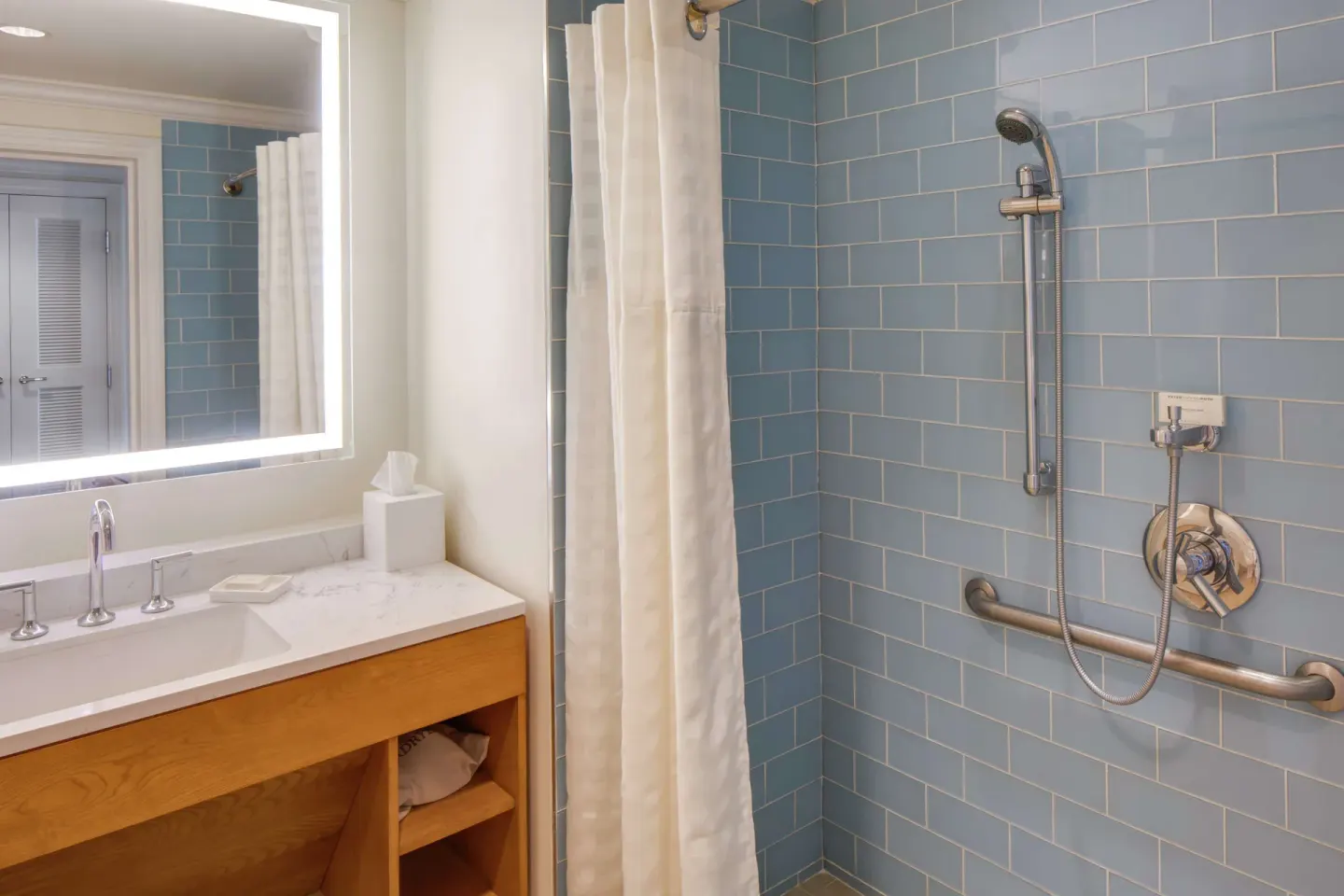 Guest bathroom with blue-tile shower and vanity at Hilton Barbados Resort.