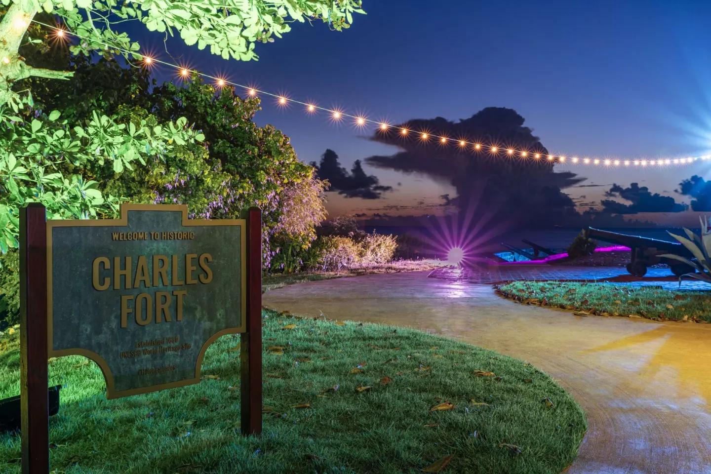 Historic Charles Fort sign and lit walkway at Hilton Barbados Resort at dusk.