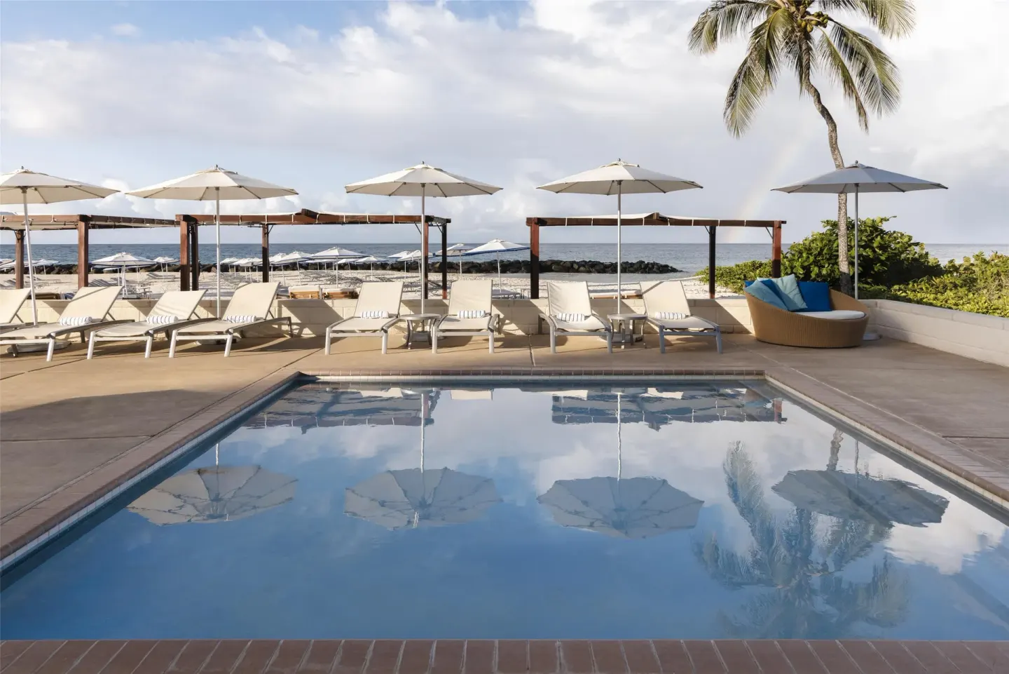 Poolside loungers and umbrellas facing the ocean at Hilton Barbados Resort.