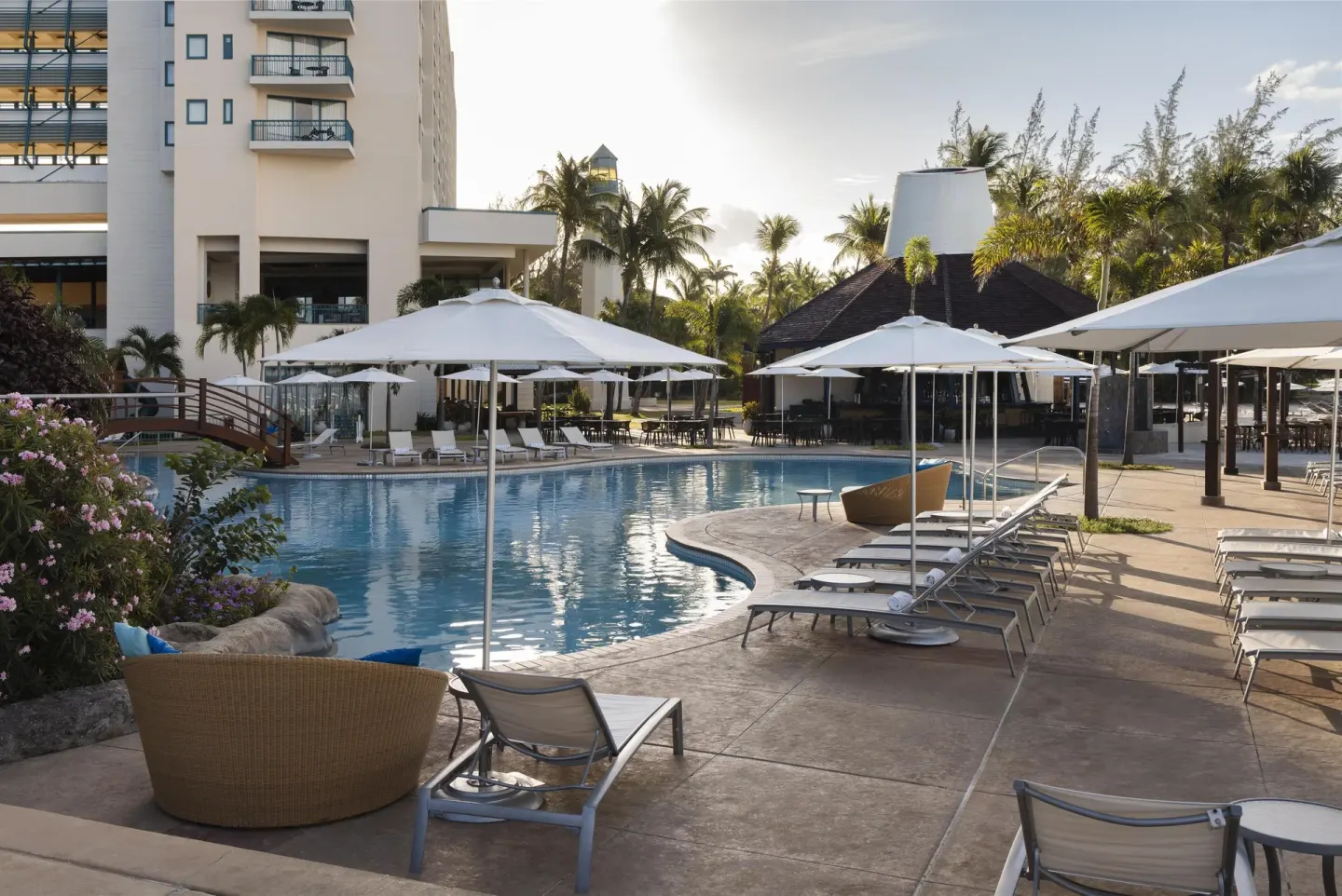 Pool deck with loungers, umbrellas and resort buildings at Hilton Barbados Resort.