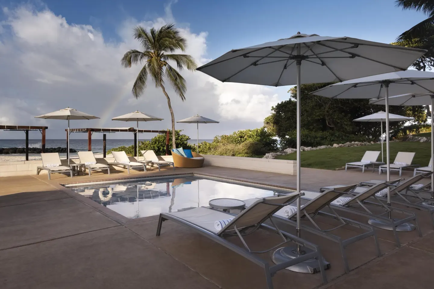 Quiet pool deck with umbrellas, loungers and ocean backdrop at Hilton Barbados Resort.