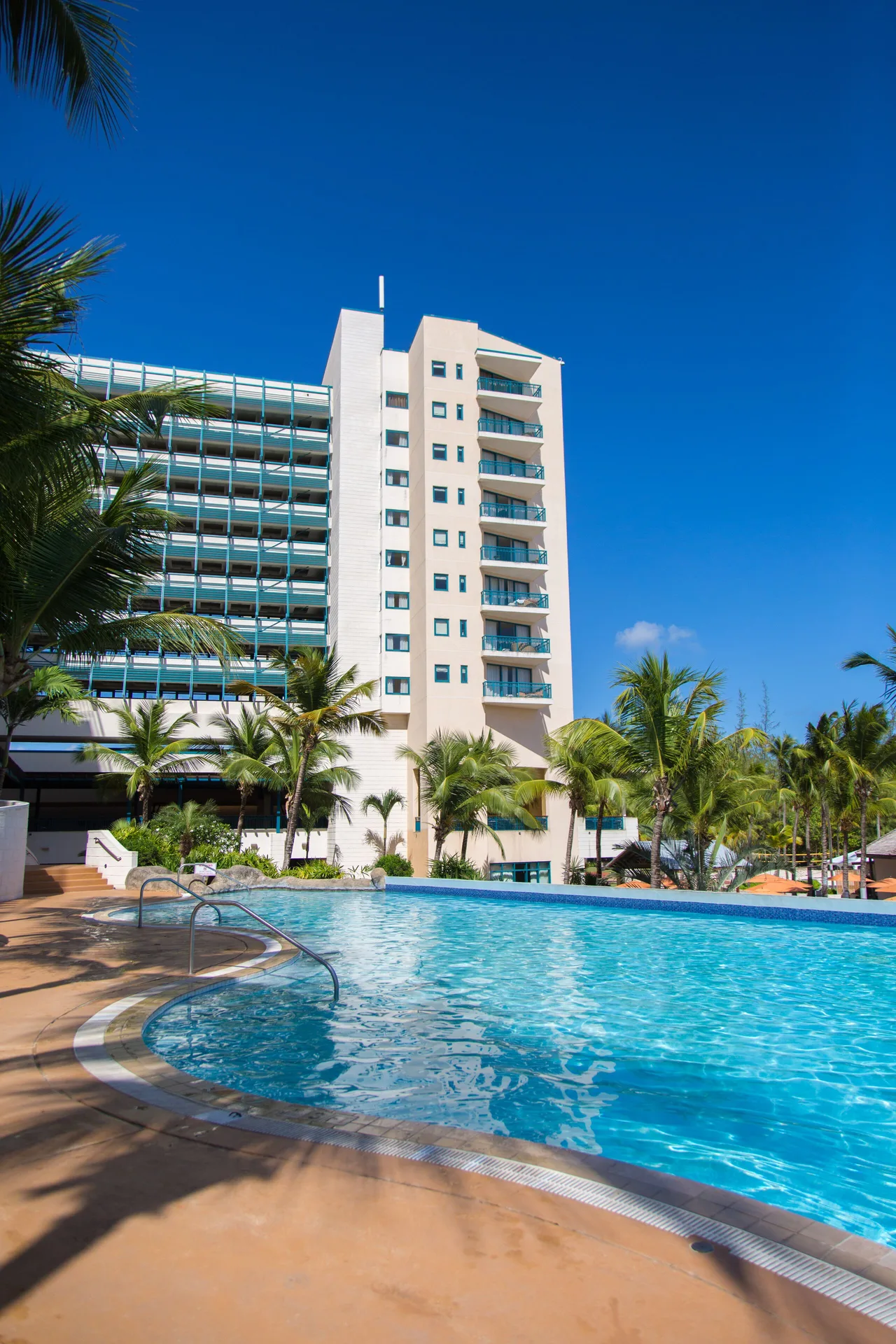 Resort pool with palm trees and guest tower at Hilton Barbados Resort.
