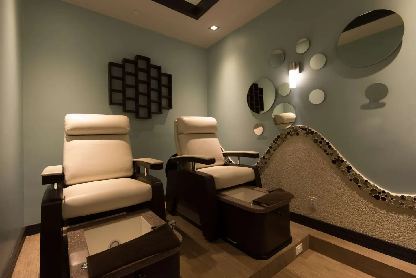 Two spa pedicure chairs with foot basins and round wall mirrors at Hilton Barbados Resort.