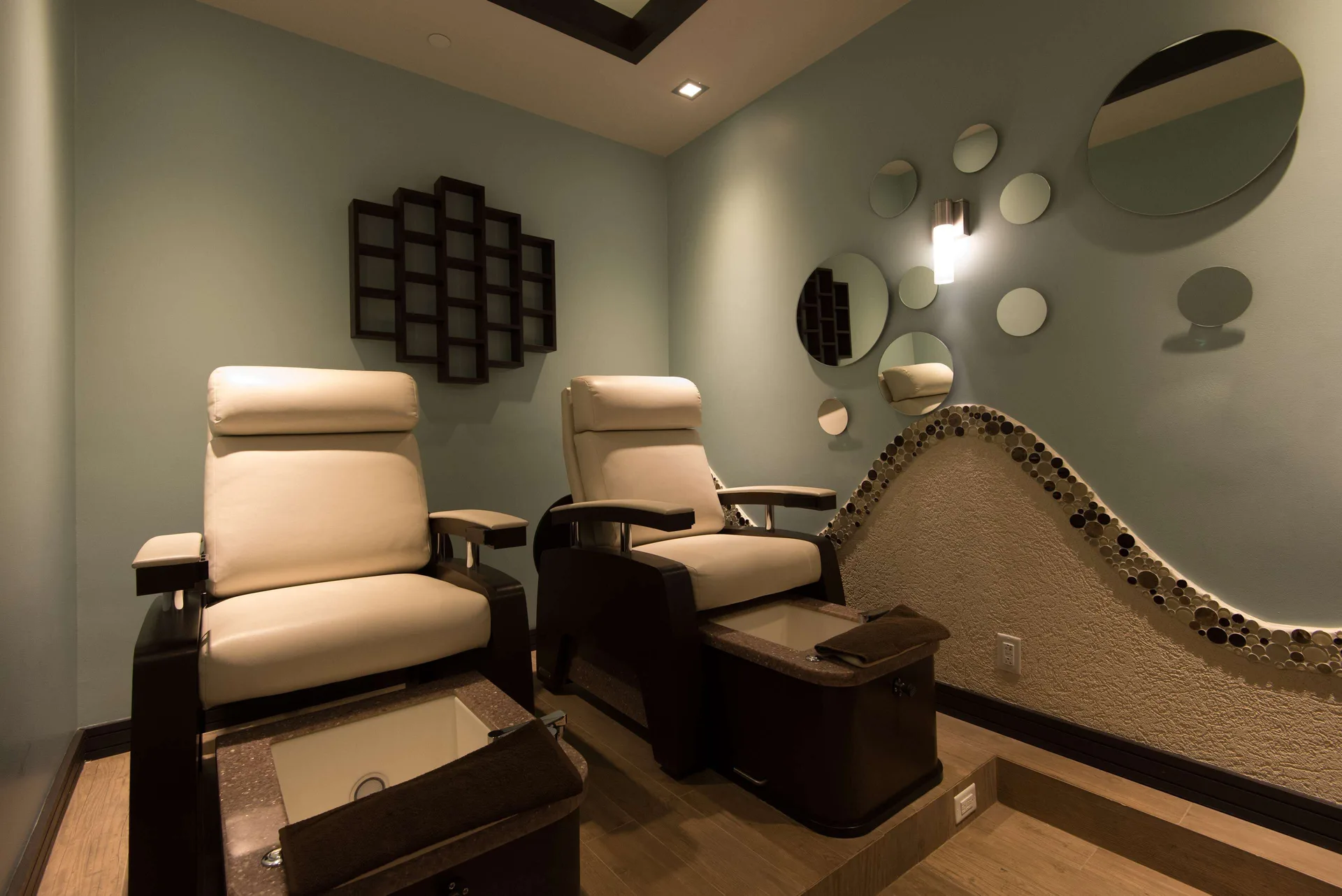 Two spa pedicure chairs with foot basins and round wall mirrors at Hilton Barbados Resort.