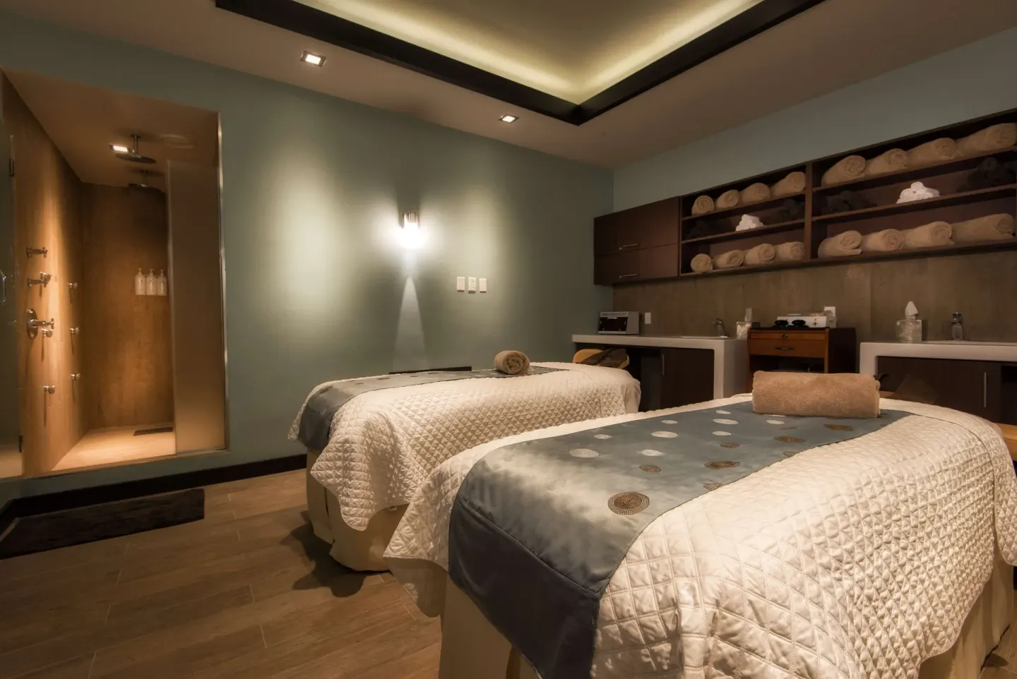 Two spa treatment beds with towels, sinks, and a shower area at Hilton Barbados Resort.