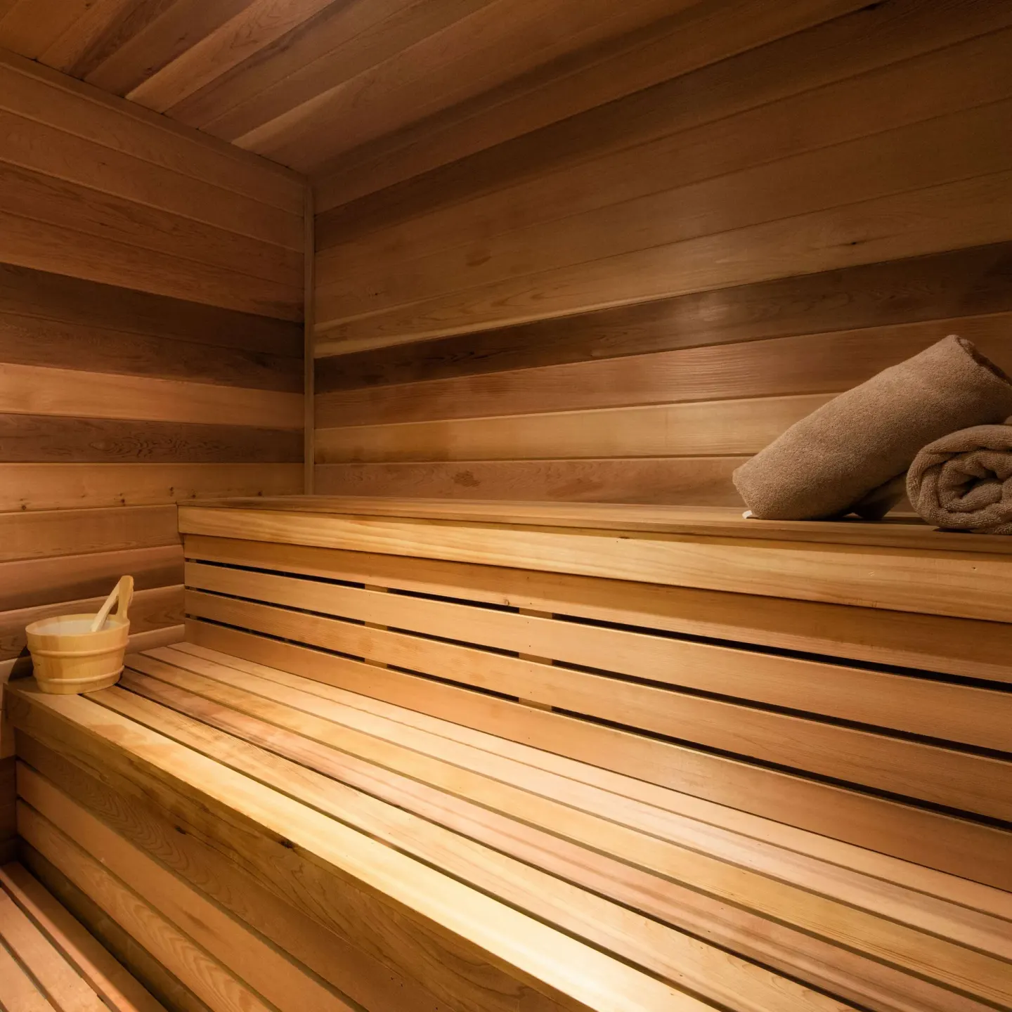 Wood-lined sauna with benches, towels and bucket at Hilton Barbados Resort.
