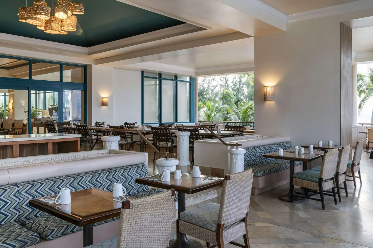 Dining tables and banquette seating in an airy restaurant at Hilton Barbados Resort.