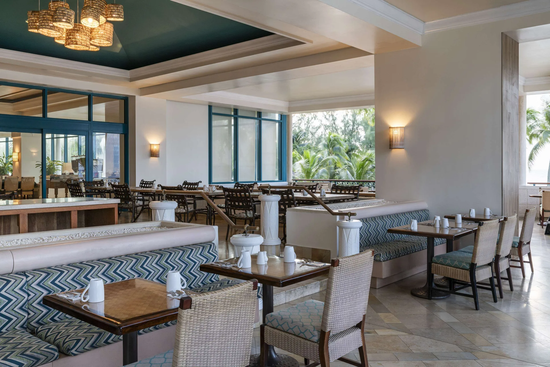Dining tables and banquette seating in an airy restaurant at Hilton Barbados Resort.