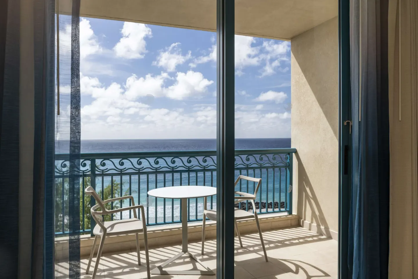 Ocean-view balcony with table and chairs in a Premium Room at Hilton Barbados Resort.