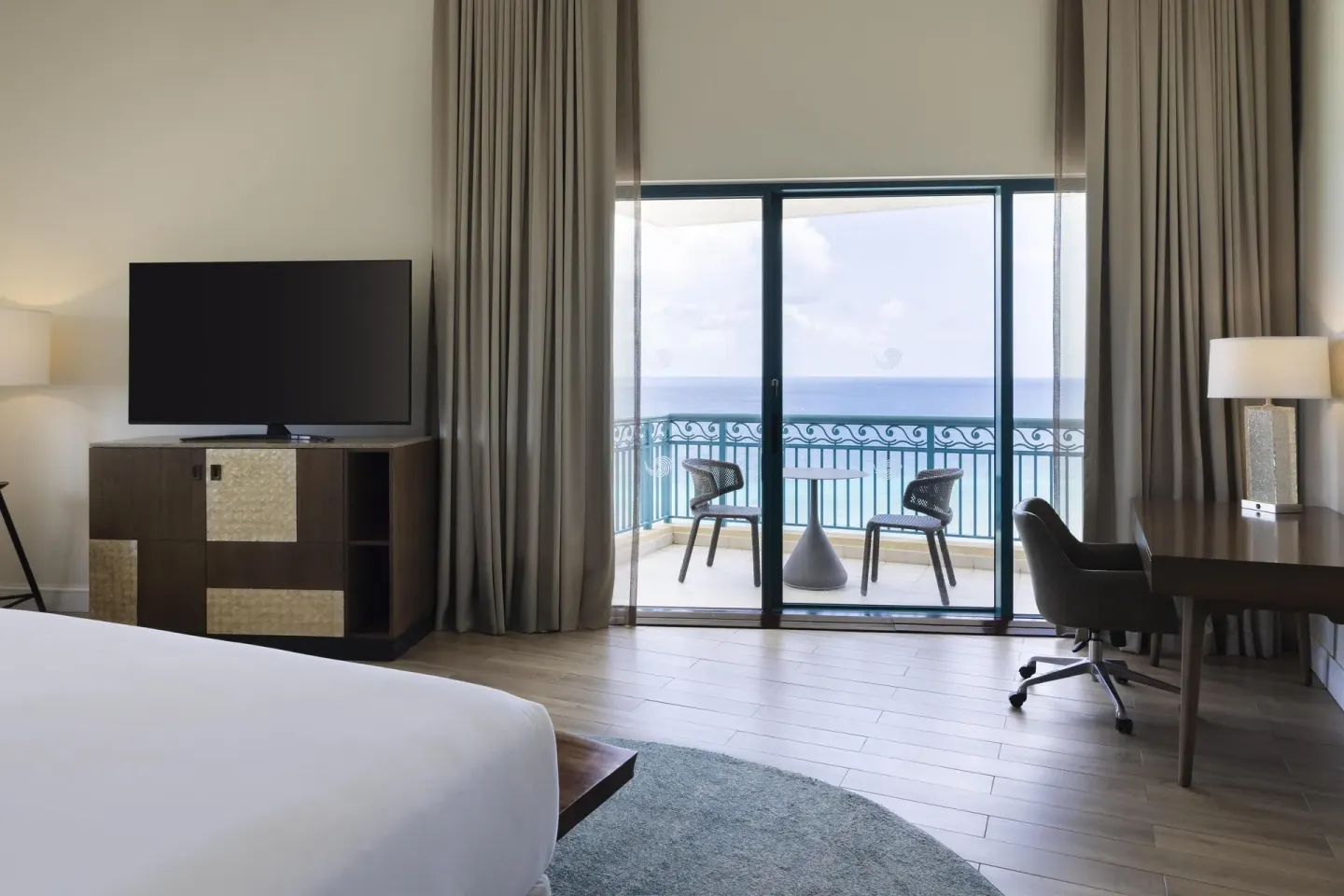 Premium suite bedroom with balcony, TV and ocean view at Hilton Barbados Resort.