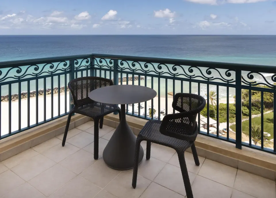 Premium Suite corner balcony with two chairs and ocean beyond at Hilton Barbados Resort.