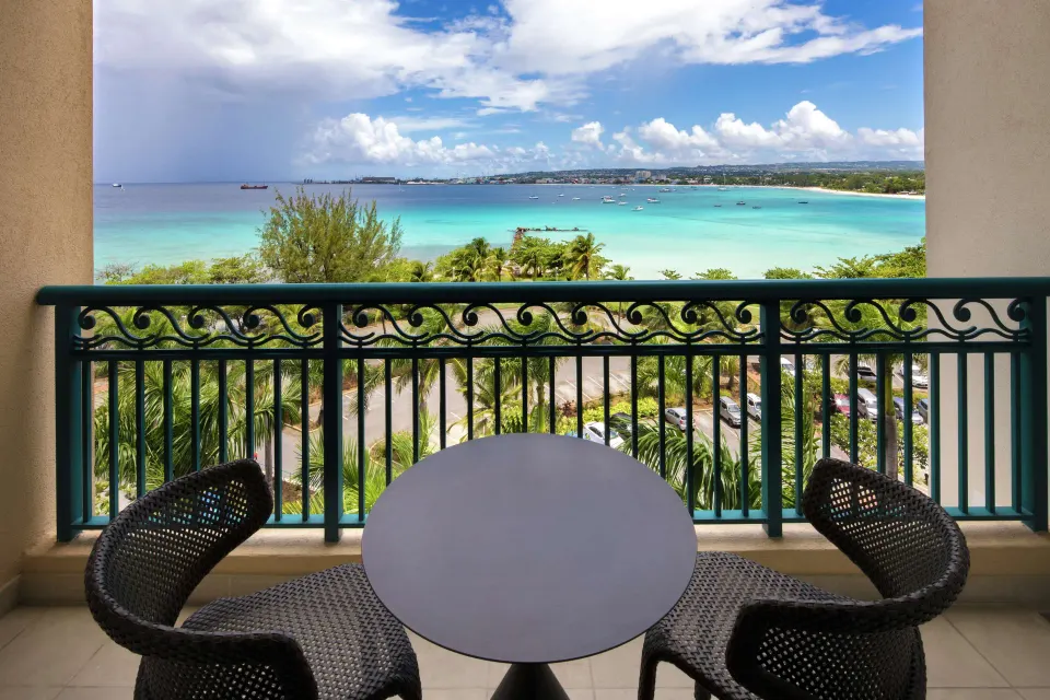Bay View room balcony at Hilton Barbados Resort with table, chairs, and turquoise water beyond.