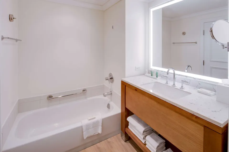 Room Bay View bathroom at Hilton Barbados Resort with bathtub, vanity, and illuminated mirror.