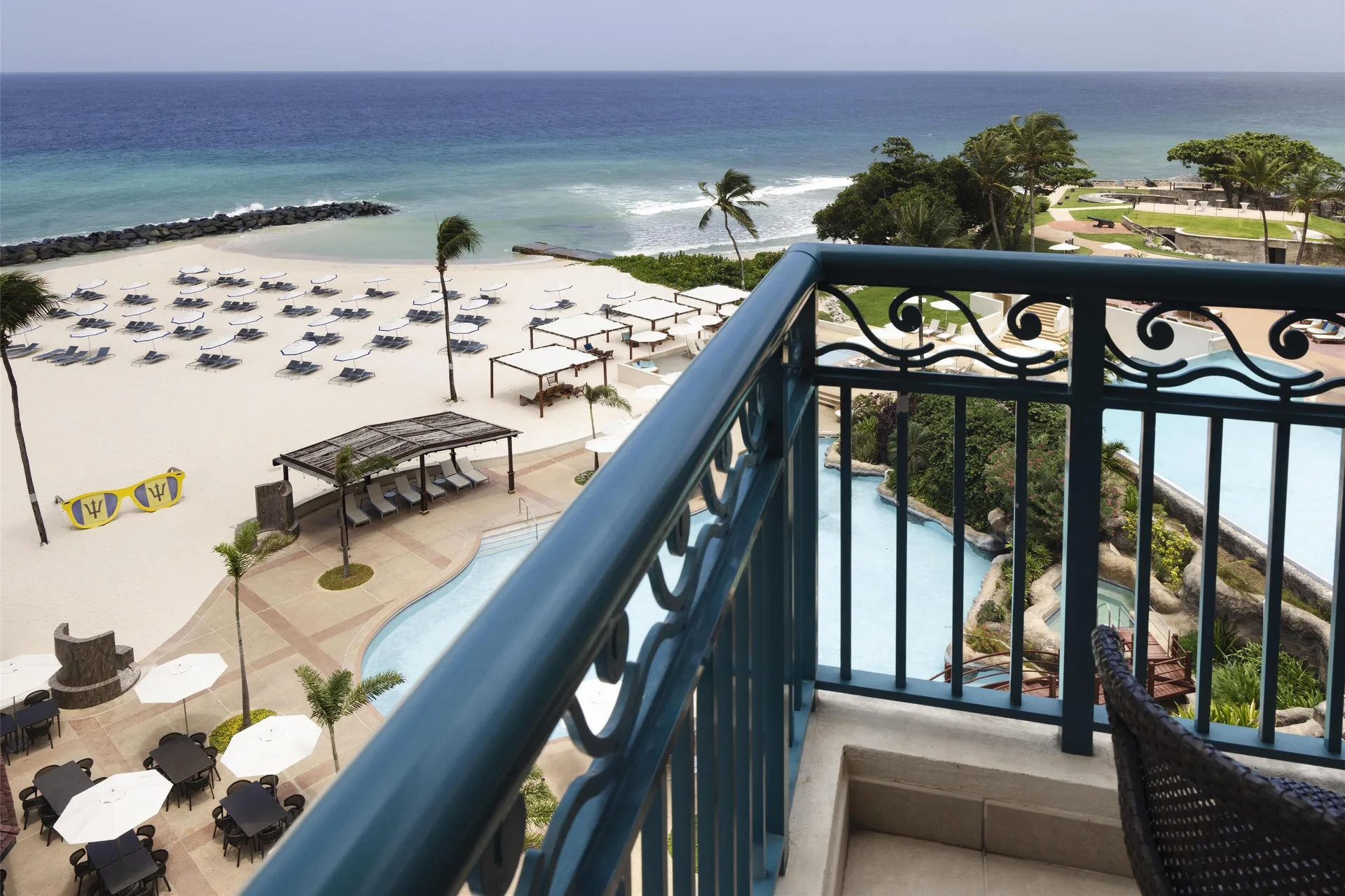 Corner room balcony overlooking beach, pool, and ocean at Hilton Barbados Resort.
