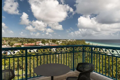 Corner room balcony with table, chairs, ocean, and island views at Hilton Barbados Resort.