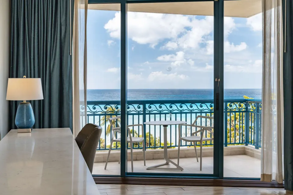 Corner room balcony with ocean view and table seating at Hilton Barbados Resort.