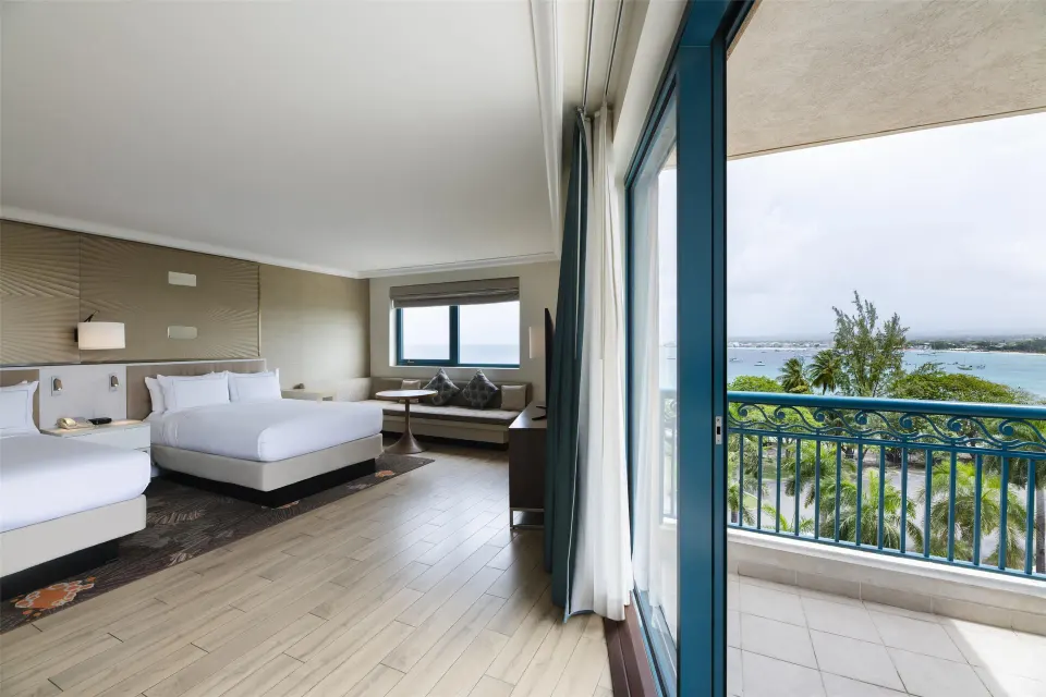 Corner room with two beds and balcony water view at Hilton Barbados Resort.