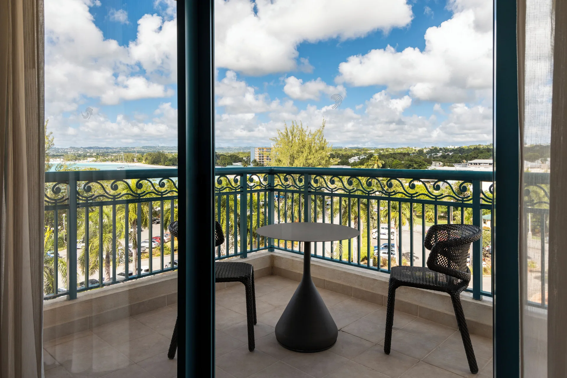 One Bedroom Suite balcony with table, chairs and coastal view at Hilton Barbados Resort.