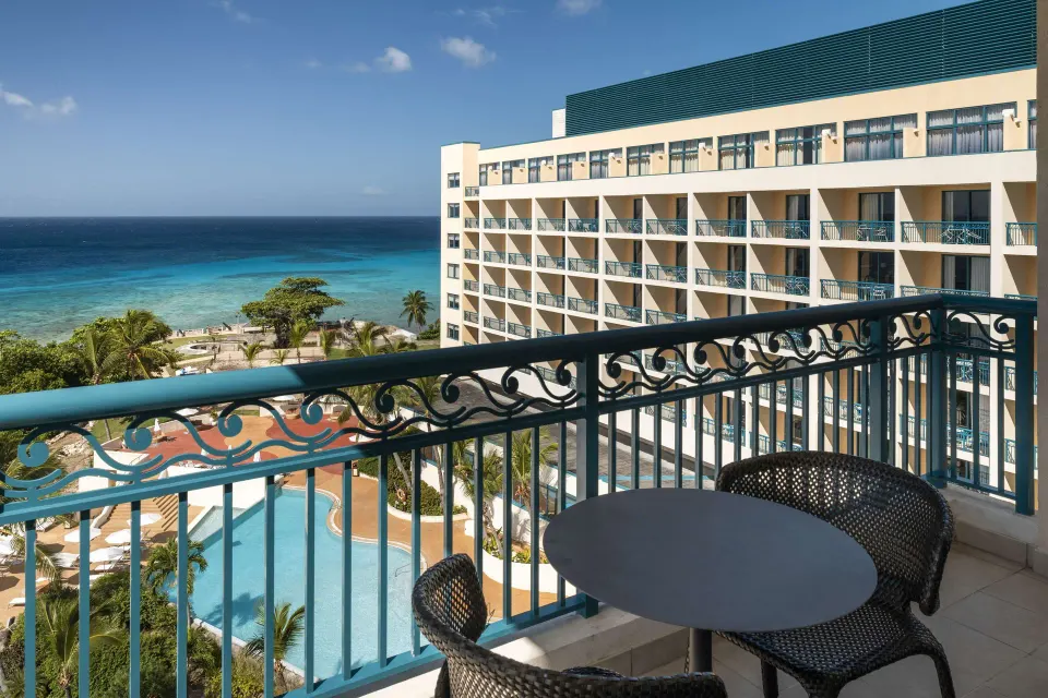 Corner suite balcony with ocean, pool, and hotel views at Hilton Barbados Resort.