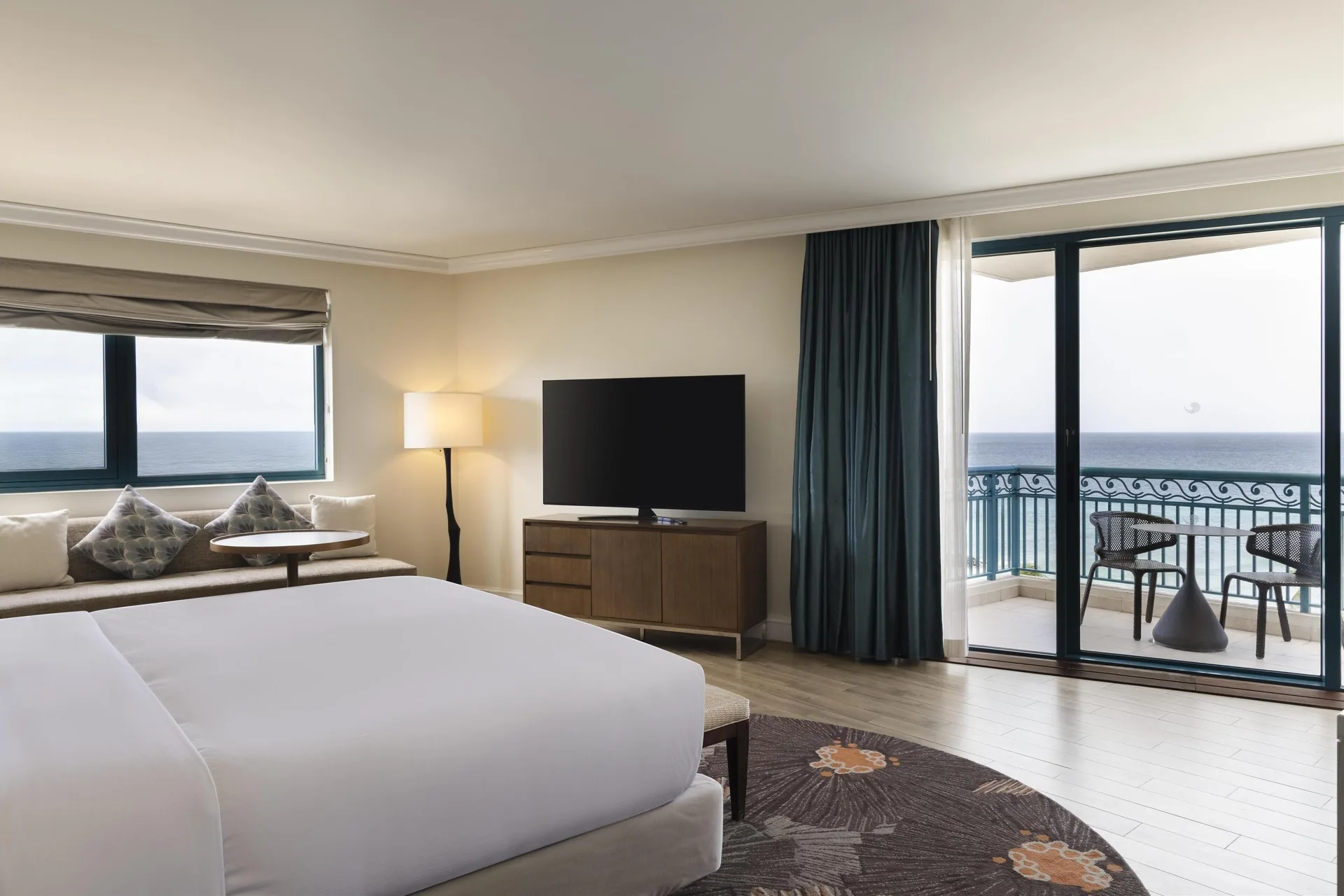 Corner ocean view suite bedroom with balcony at Hilton Barbados Resort.