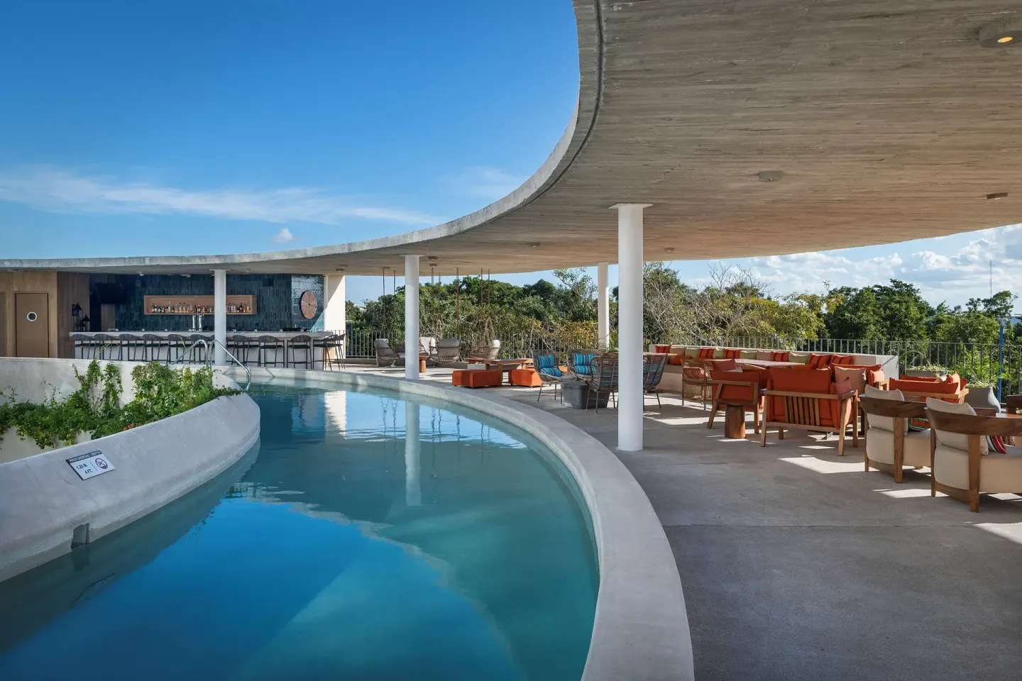 Covered pool terrace with seating and a bar at Hilton Garden Inn Cancun Airport.