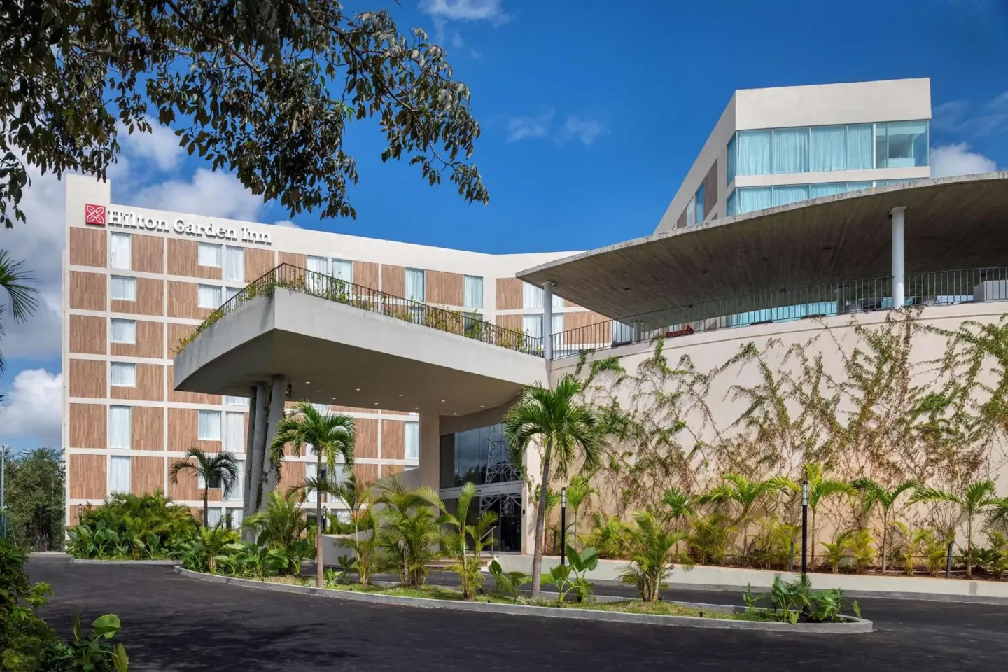 Curved hotel facade and covered entrance at Hilton Garden Inn Cancun Airport.