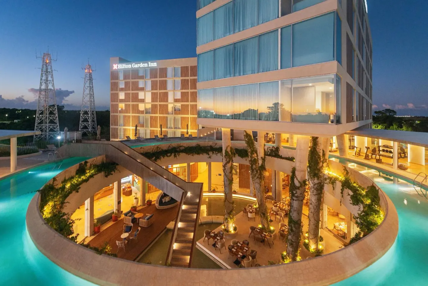 Evening exterior with pools and courtyard at Hilton Garden Inn Cancun Airport.