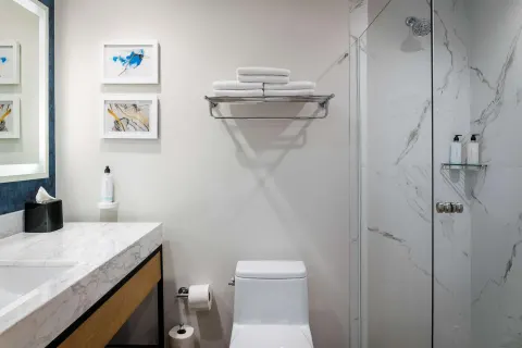 Guest bathroom with marble vanity and glass shower at Hilton Garden Inn Cancun Airport.