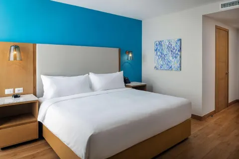Guest room with a king bed and blue accent wall at Hilton Garden Inn Cancun Airport.