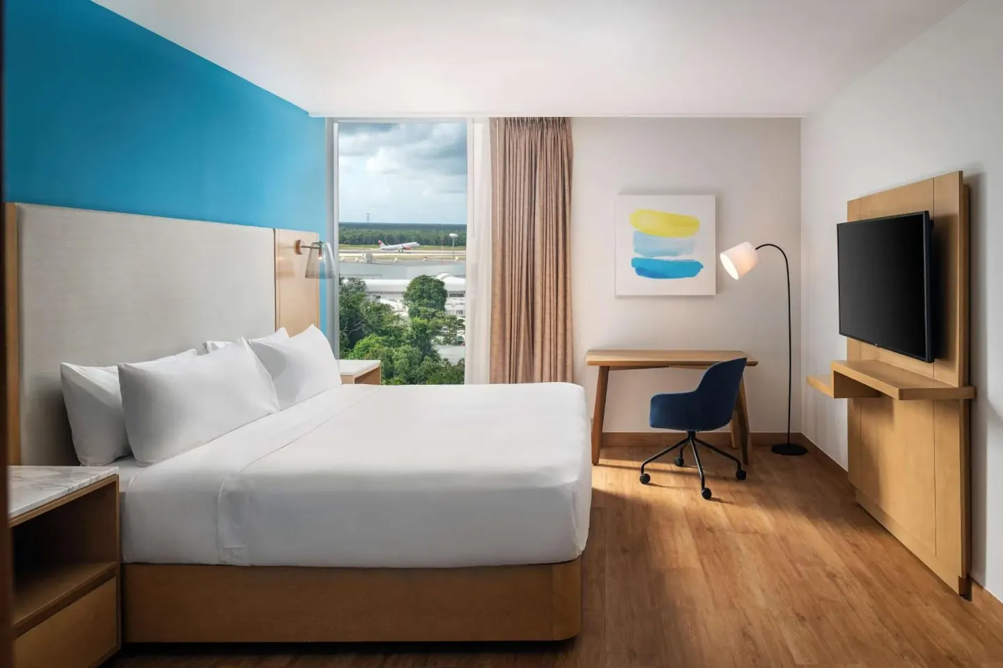 King guest room with desk and runway view at Hilton Garden Inn Cancun Airport.
