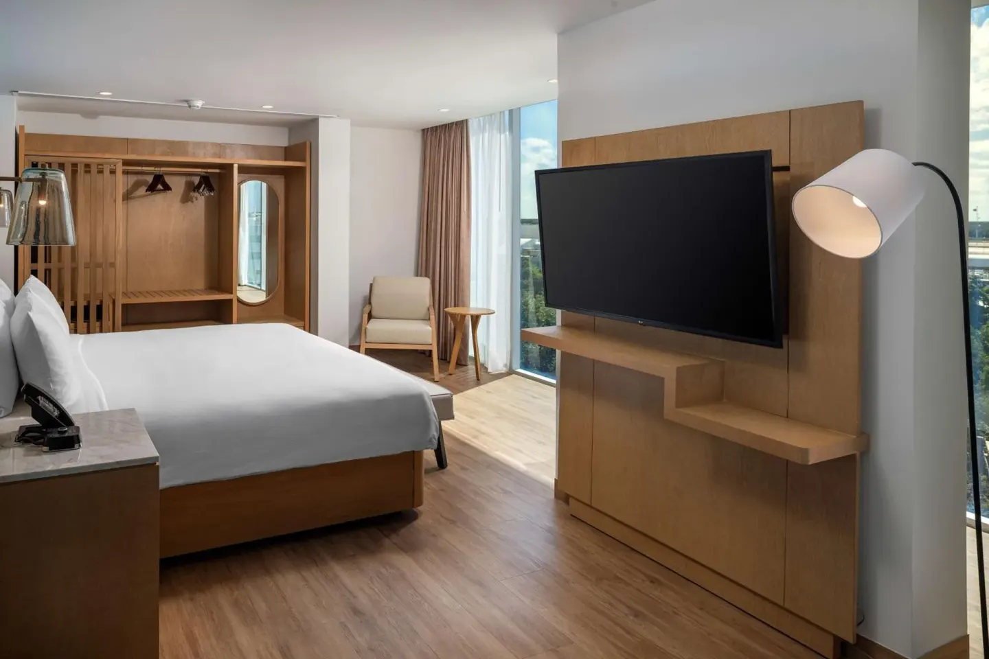 King bed guest room with open closet and large TV at Hilton Garden Inn Cancun Airport.