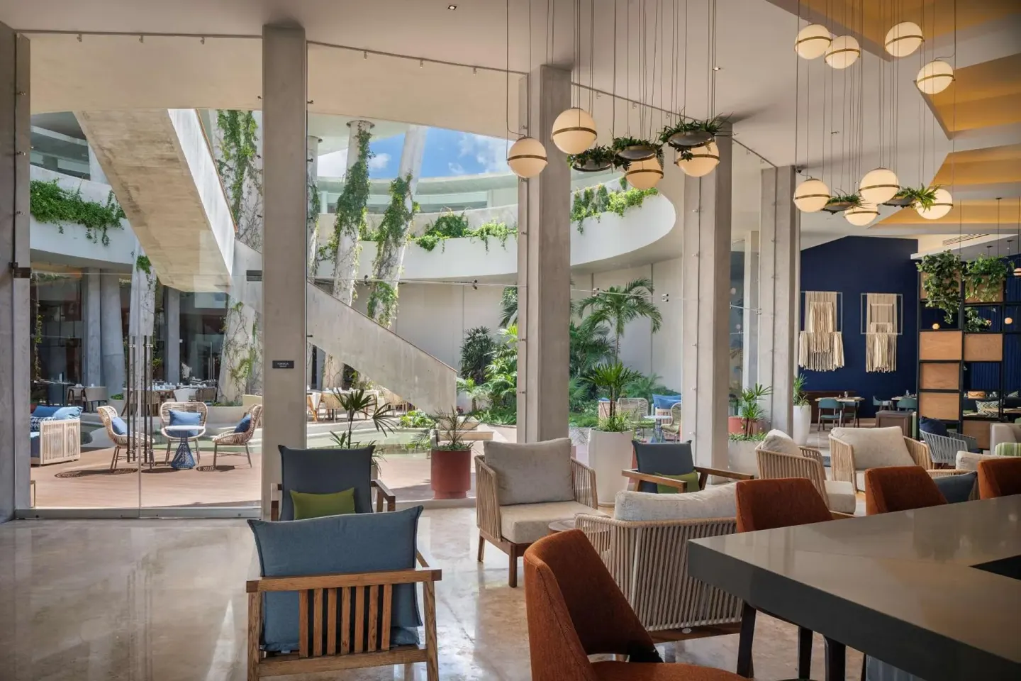 Lobby lounge seating beside glass courtyard walls at Hilton Garden Inn Cancun Airport.