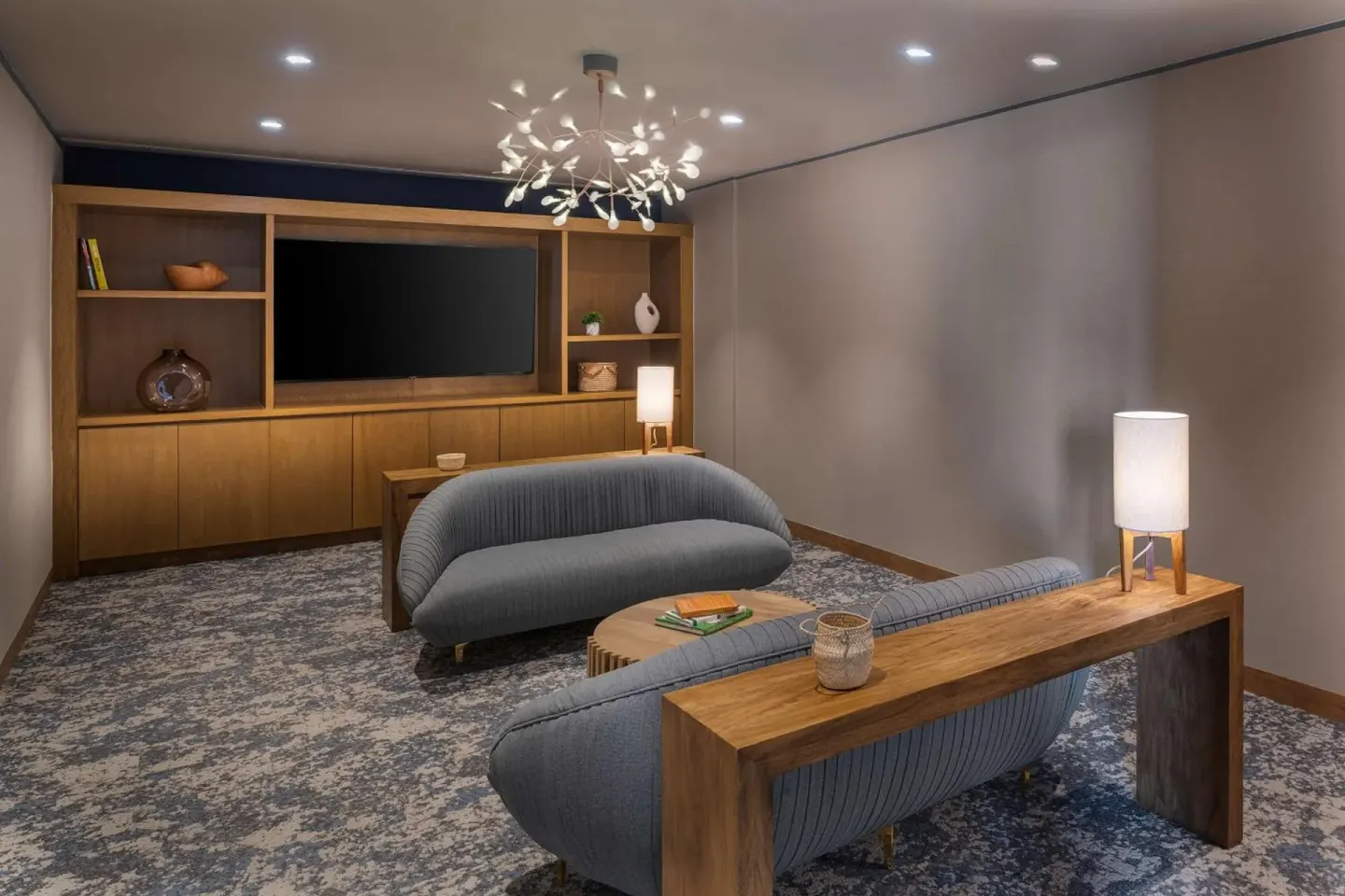 Lounge seating area with sofas, TV, and built-in shelves at Hilton Garden Inn Cancun Airport.