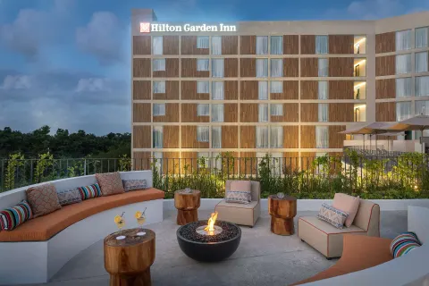 Outdoor terrace lounge with fire pit at Hilton Garden Inn Cancun Airport.
