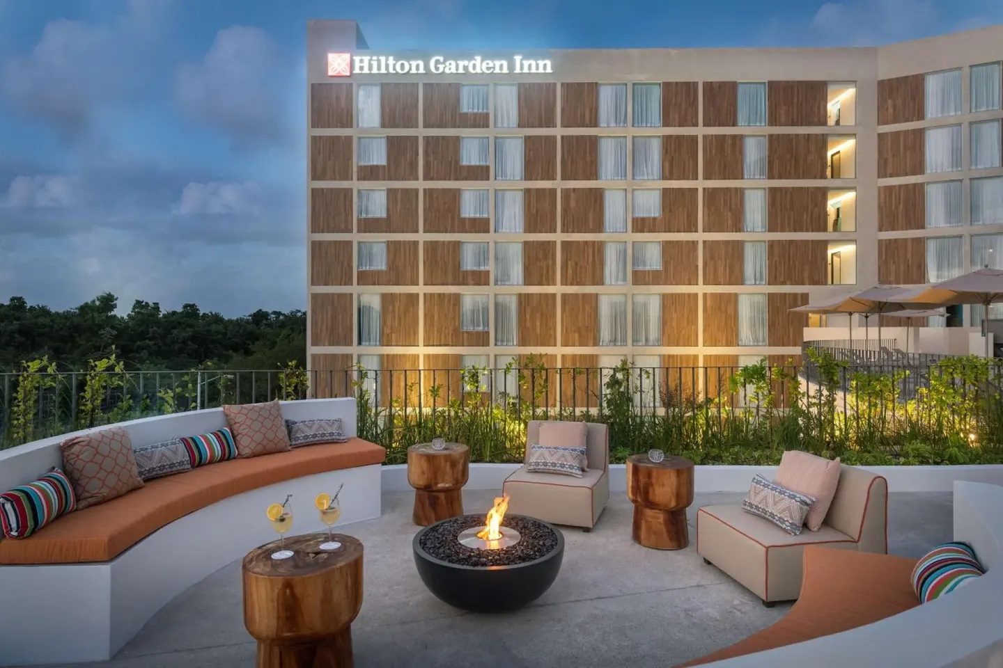 Outdoor terrace seating with fire feature at Hilton Garden Inn Cancun Airport.