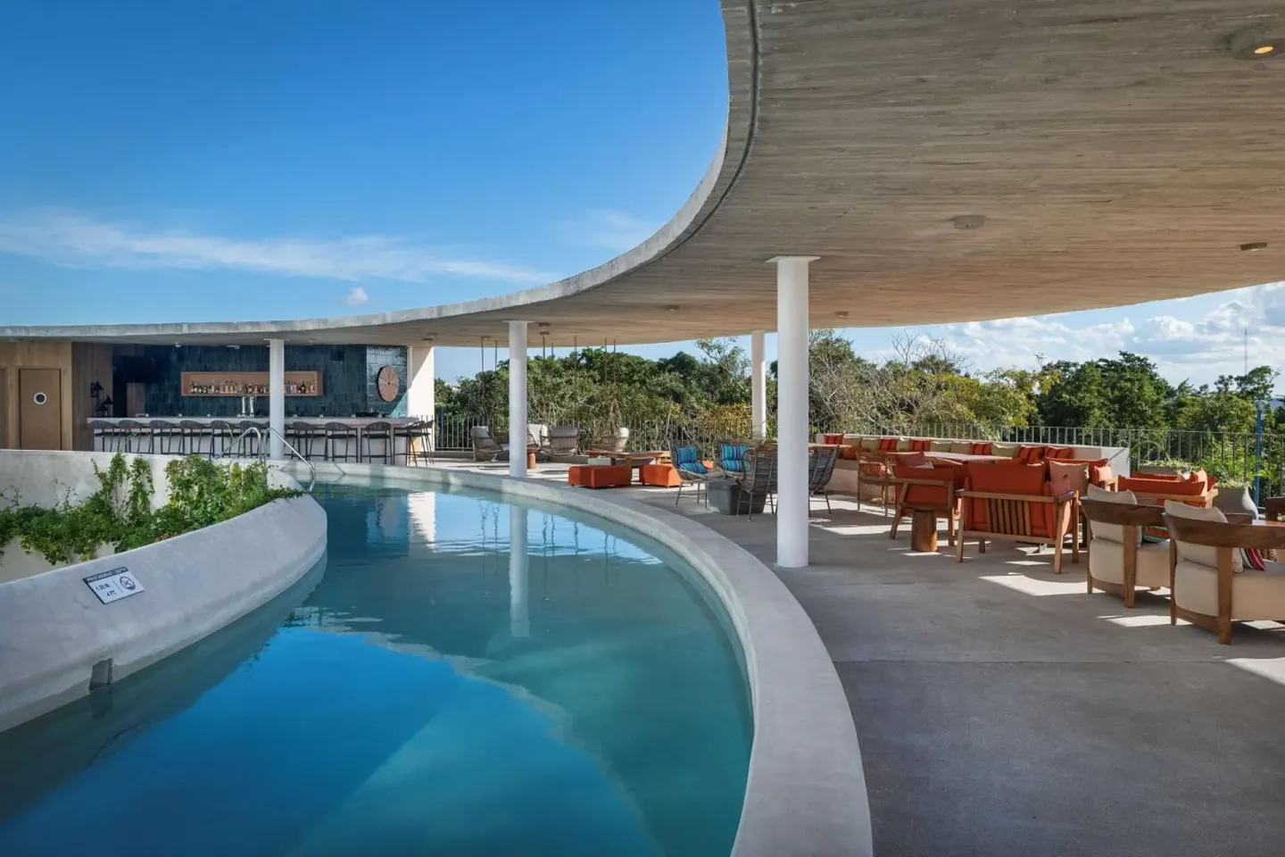 Curved pool terrace with lounge seating and bar at Hilton Garden Inn Cancun Airport.