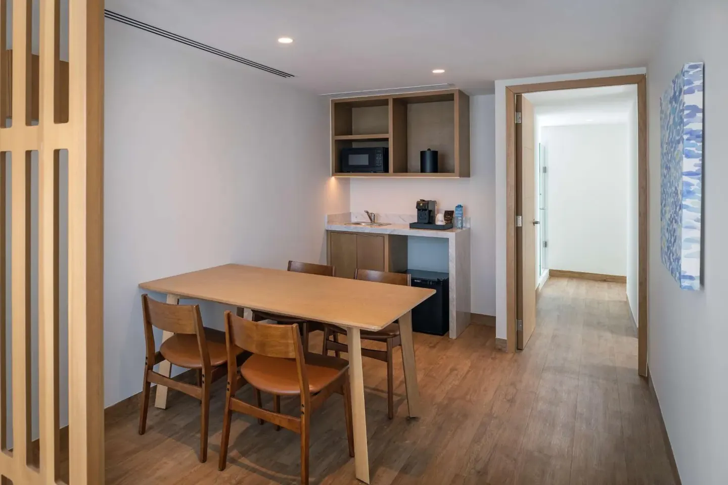Suite dining area with table, chairs, and kitchenette at Hilton Garden Inn Cancun Airport.