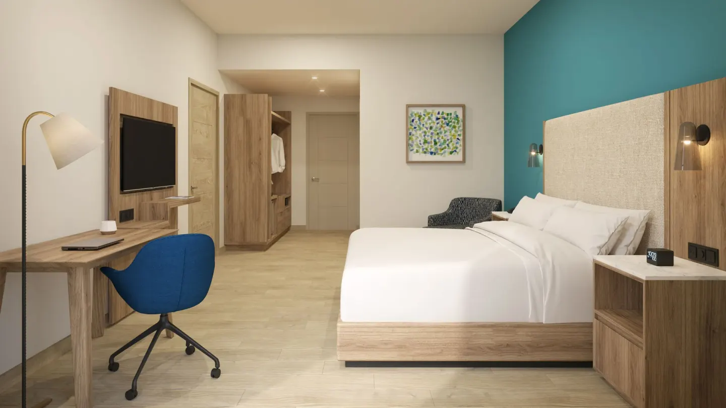 King guest room with desk and teal accent wall at Hilton Garden Inn Cancun Airport.