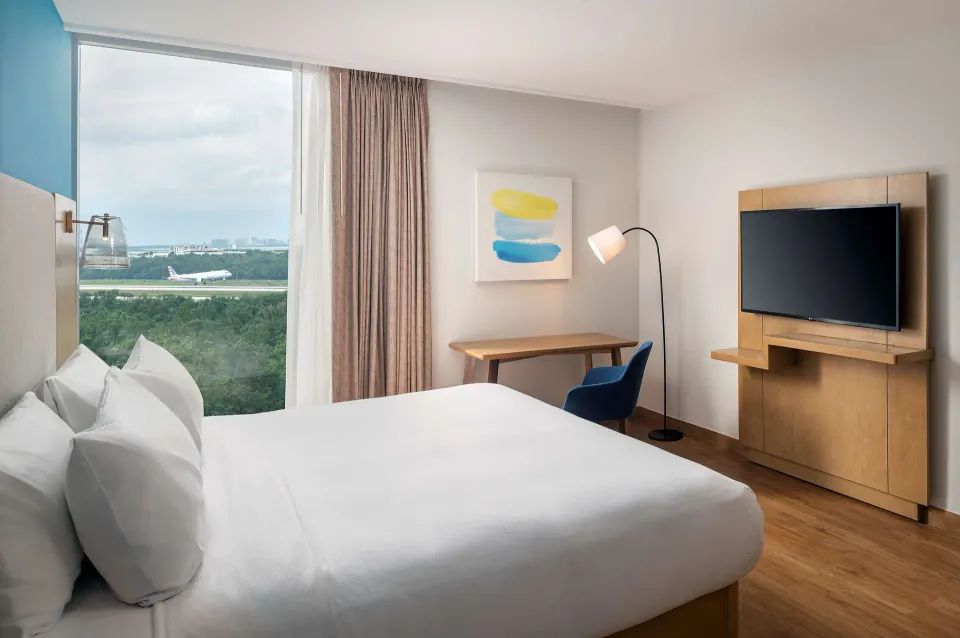 King guest room with runway view and work desk at Hilton Garden Inn Cancun Airport.