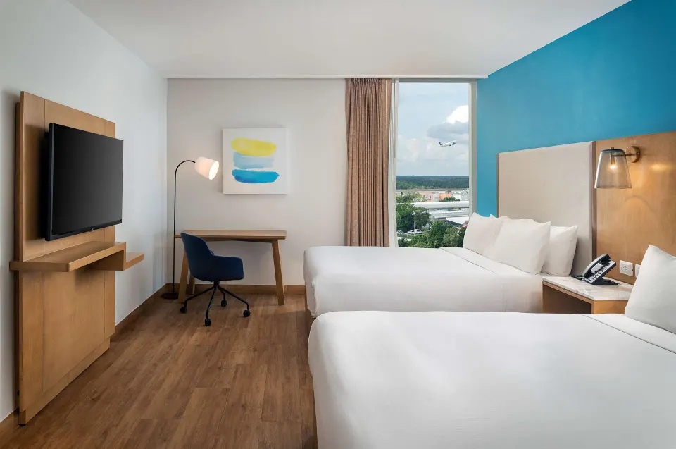 Two-bed guest room with desk and airport view at Hilton Garden Inn Cancun Airport.