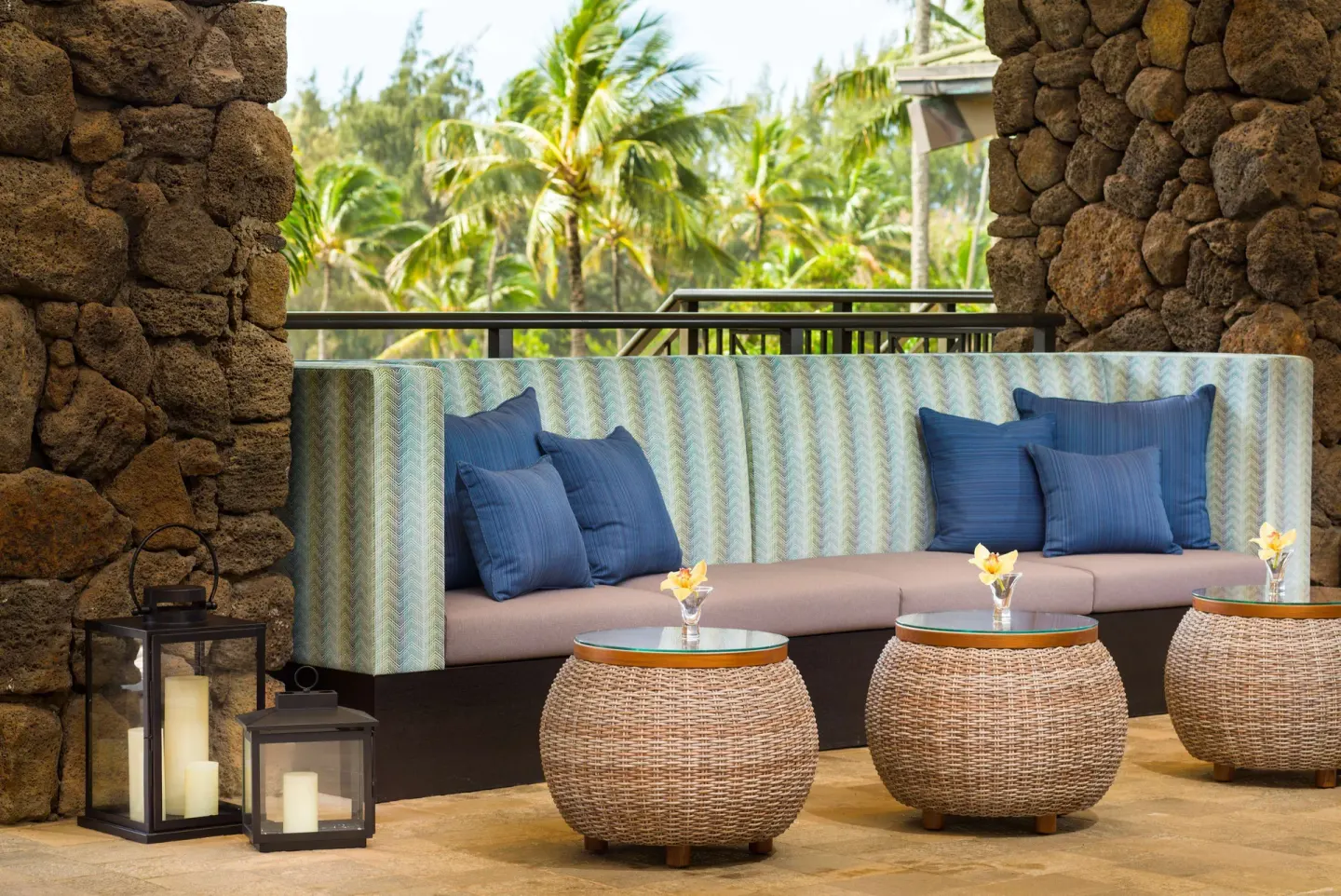 Covered lounge seating with blue pillows at Hilton Garden Inn Kauai Wailua Bay.